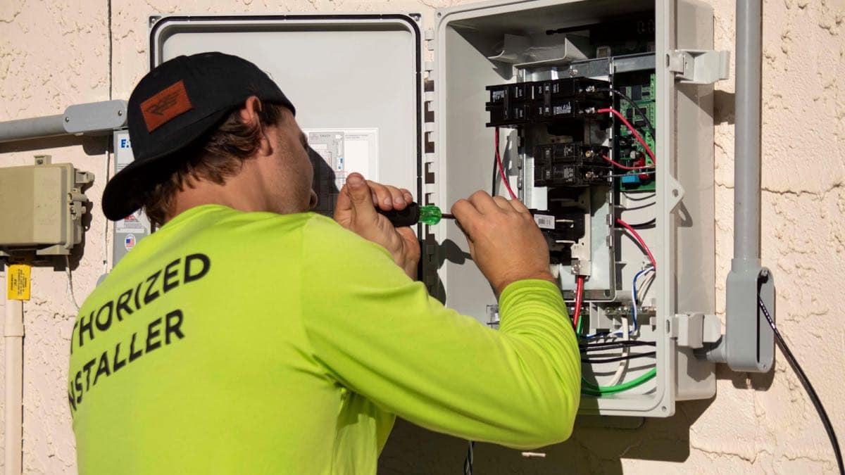 An electrician working inside an open electrical panel